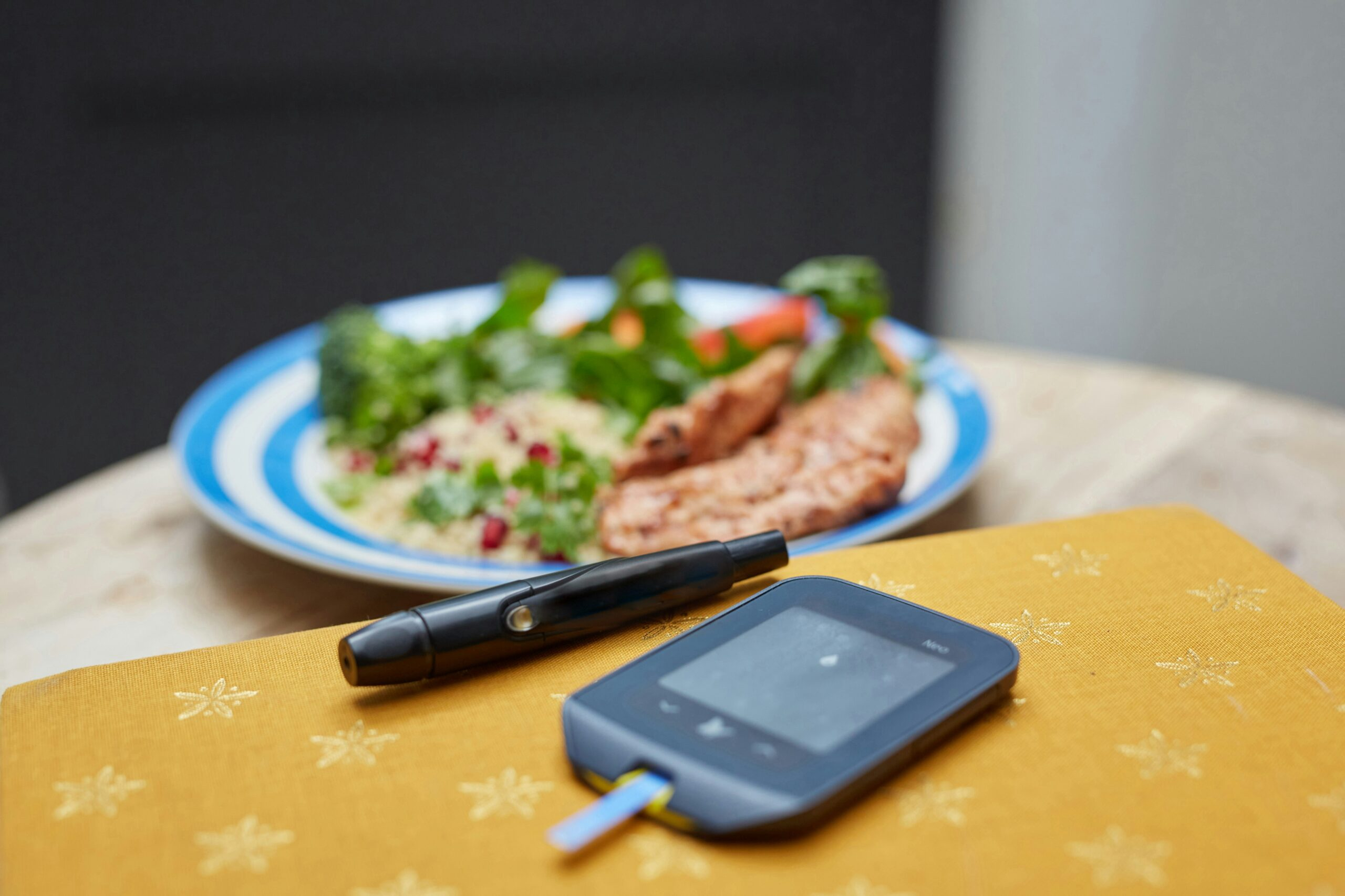 Blood glucose meter next to a balanced plate of food, representing diabetes and blood sugar nutrition support