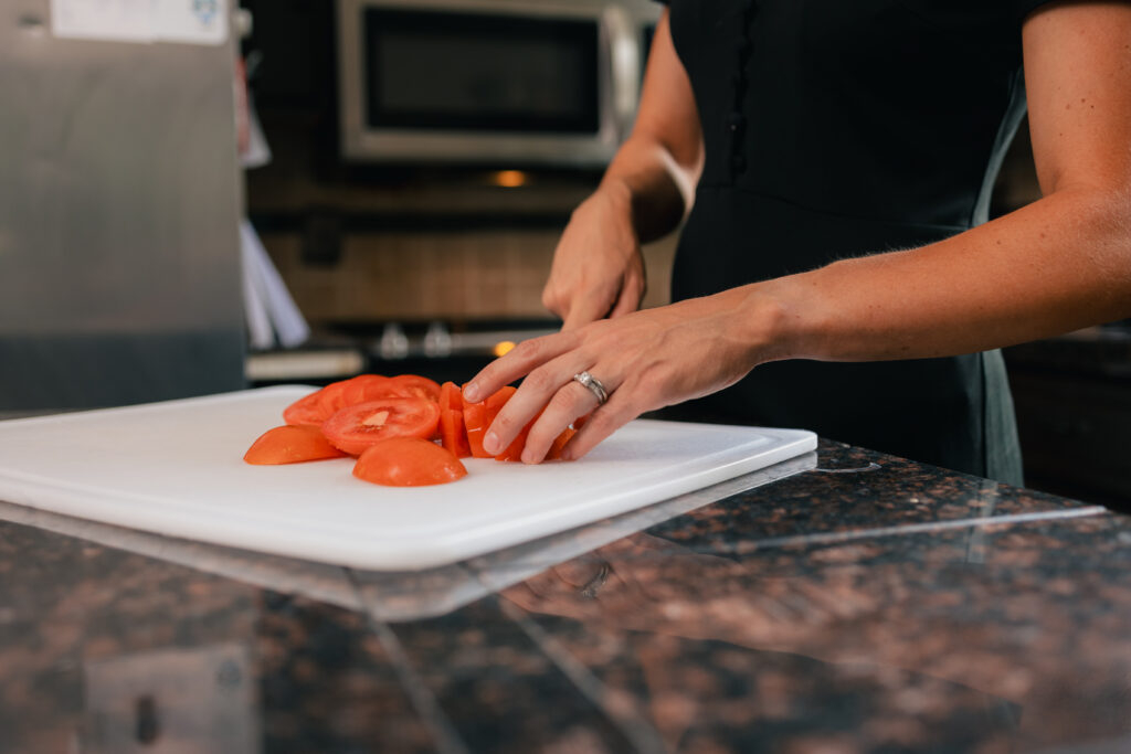 Hands slicing a fresh tomato on a cutting board, representing weight management nutrition coaching