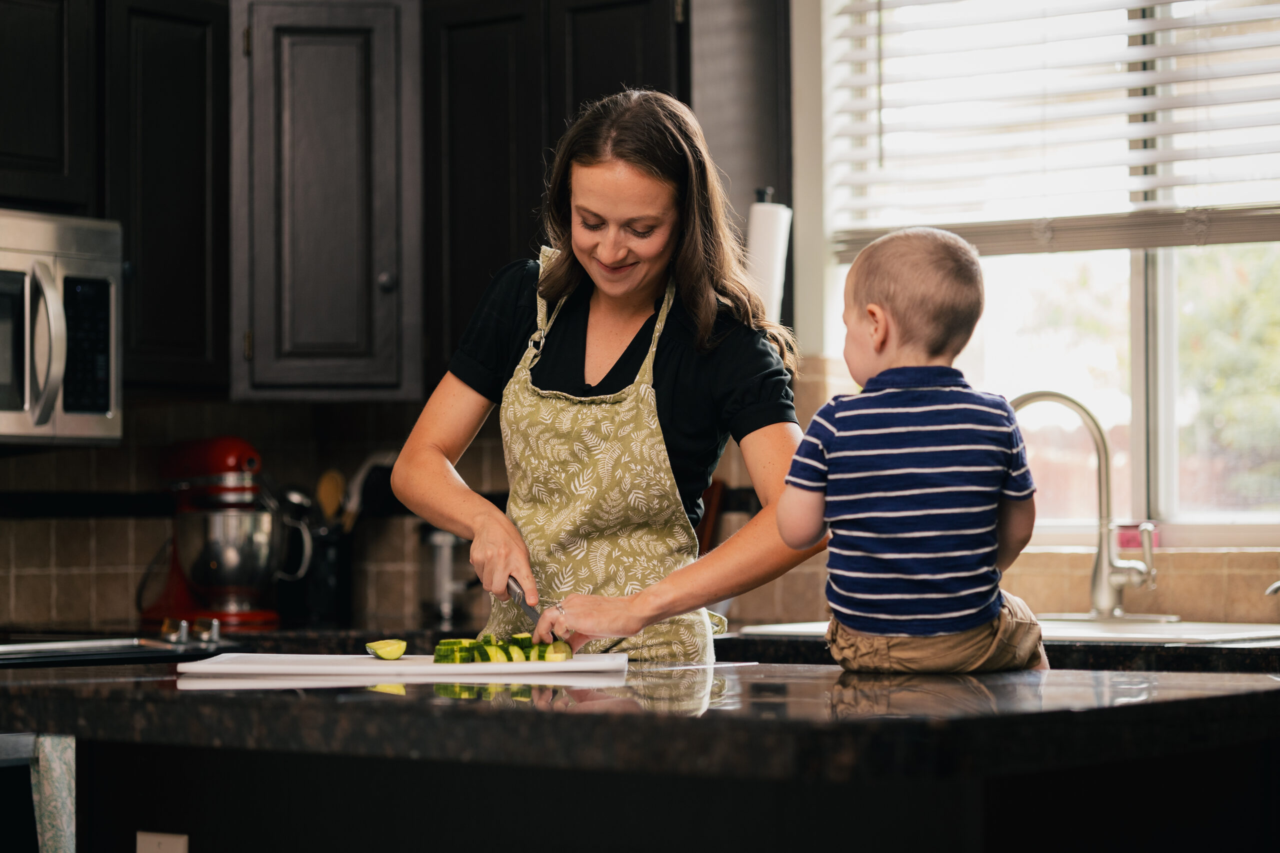 Mother preparing vegetables in the kitchen with her young child nearby, representing PCOS nutrition support